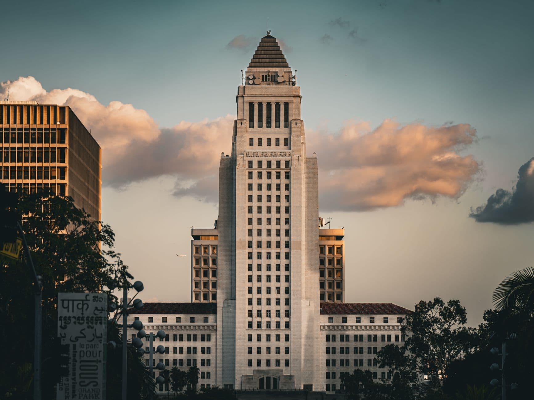 Iconic Los Angeles City Hall illuminated by a dramatic sky at sunset, showcasing urban architecture.