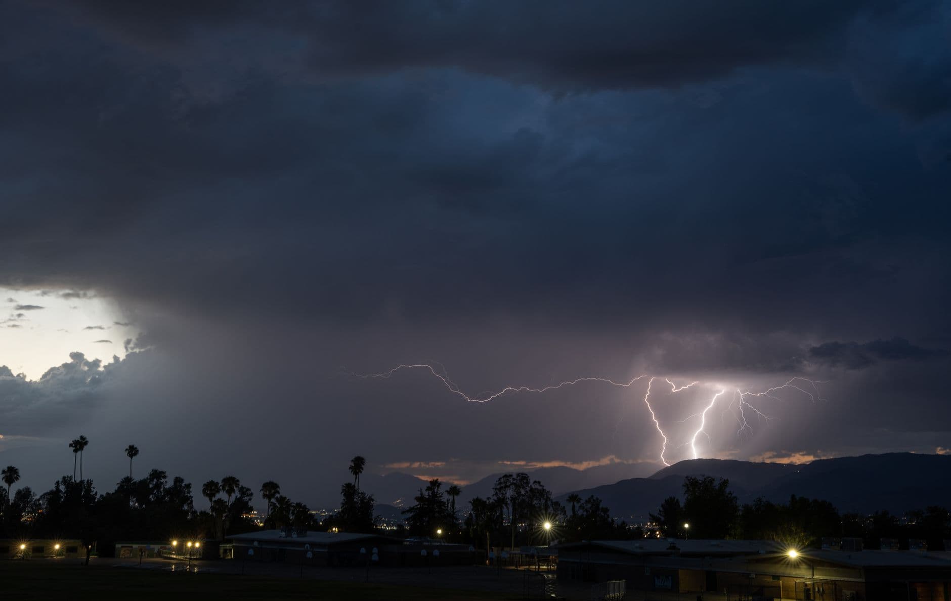 Lightning bolts illuminate the night sky with silhouetted trees in Redlands, CA.